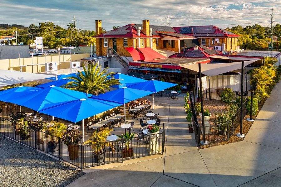 The spacious and vibrant outdoor dining area of the Esk Grand Hotel featuring bright blue umbrellas